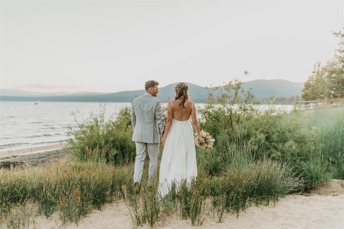 Back of bride and groom looking at each other on the shore of Lake Tahoe
