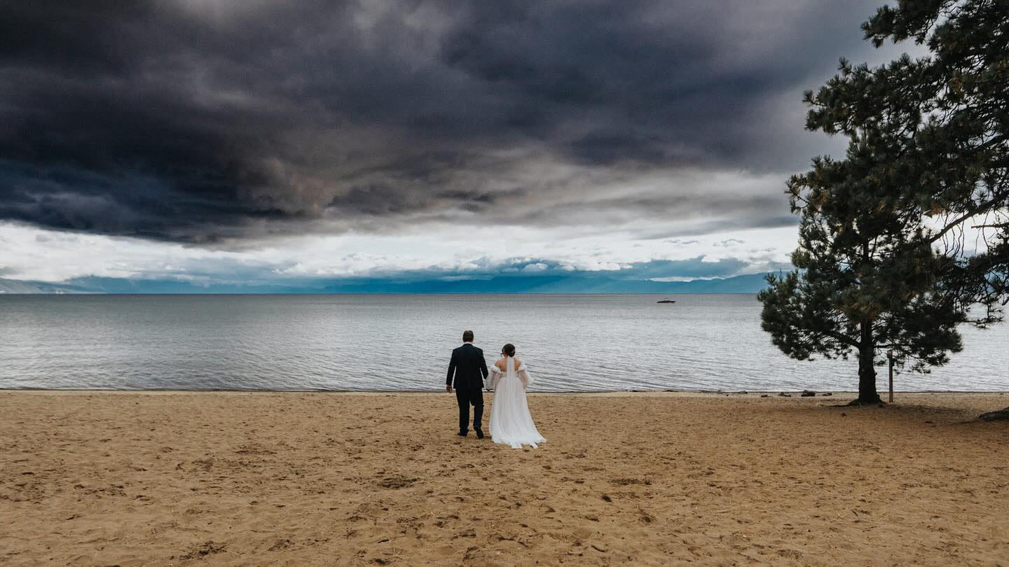 moody day on lake tahoe with bride and groom on shore