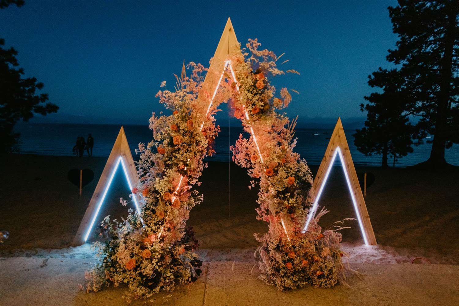 three triangles with flowers set up for a wedding ceremony backgrop