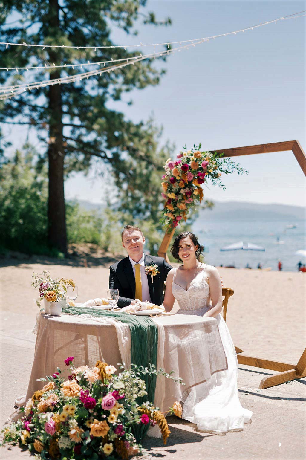 bride and groom signing license in front of lake tahoe at a beautiful table in front of floral arch