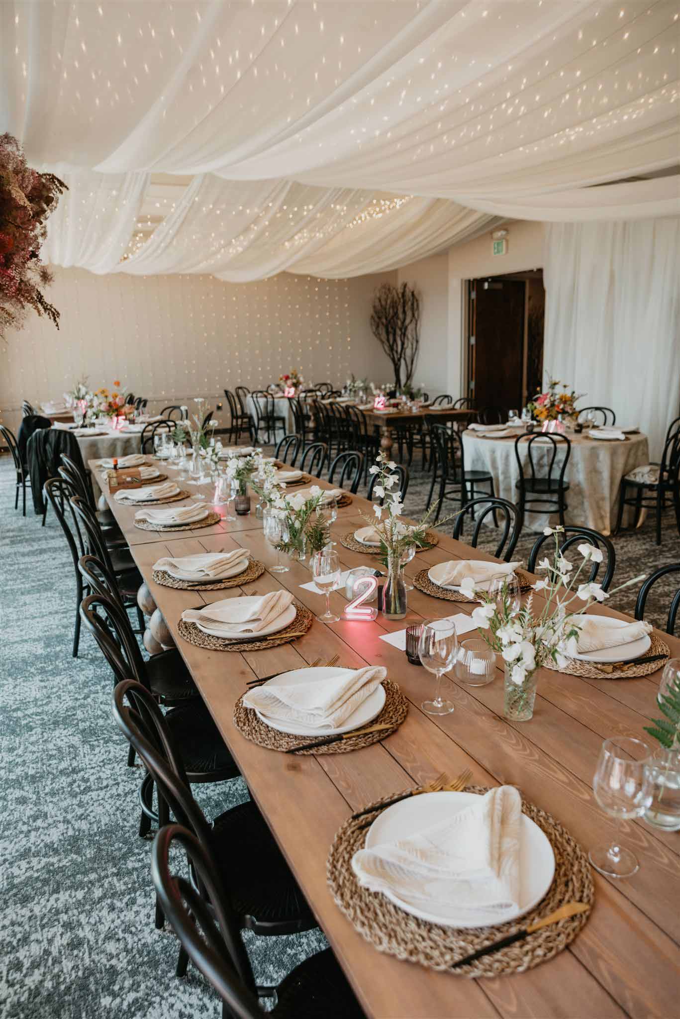 Elegant wedding dining room setup with fairy lights and fabric on the ceiling