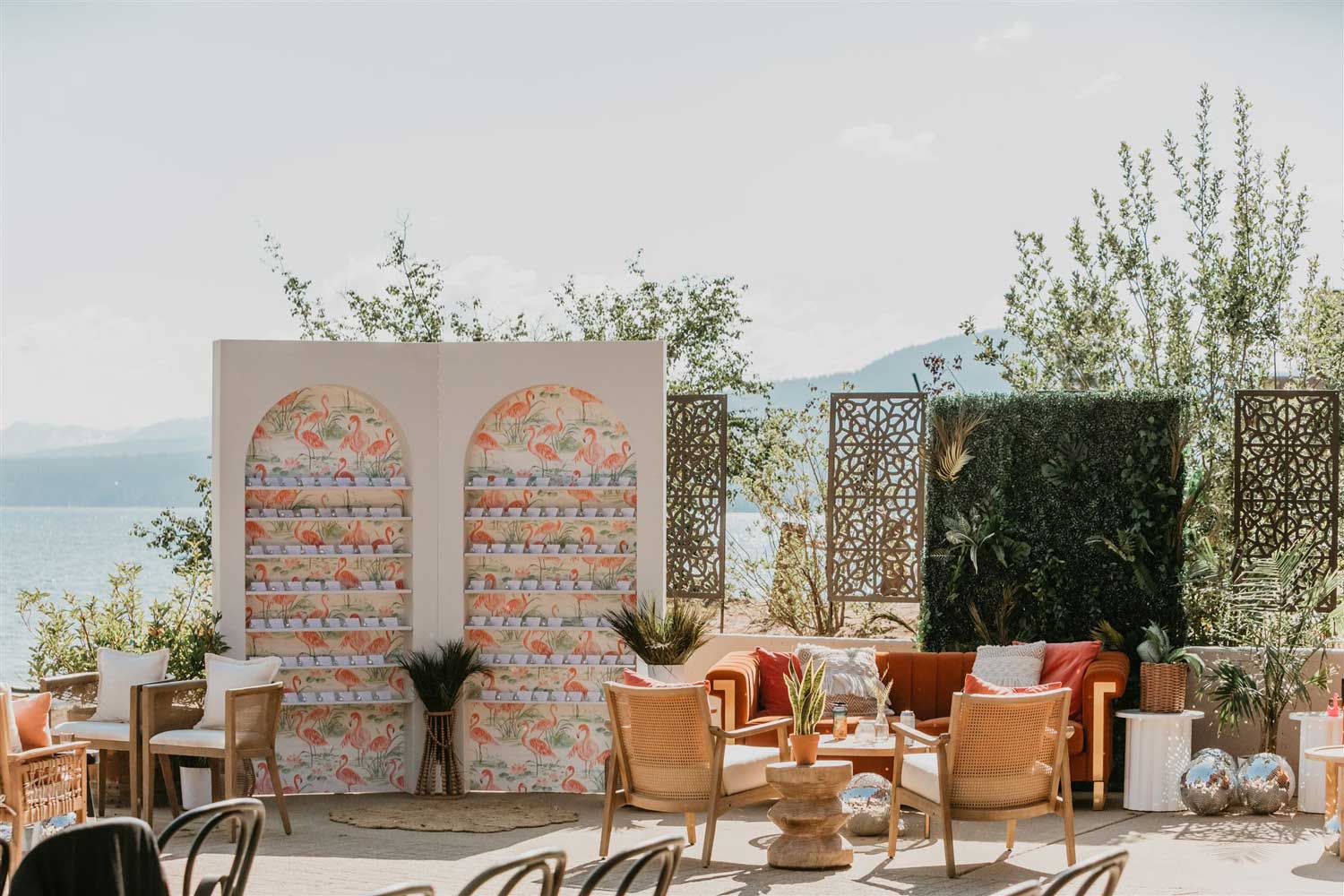 Outdoor seating area with orange decor, plants, decorative flamingos, and Lake Tahoe in the background
