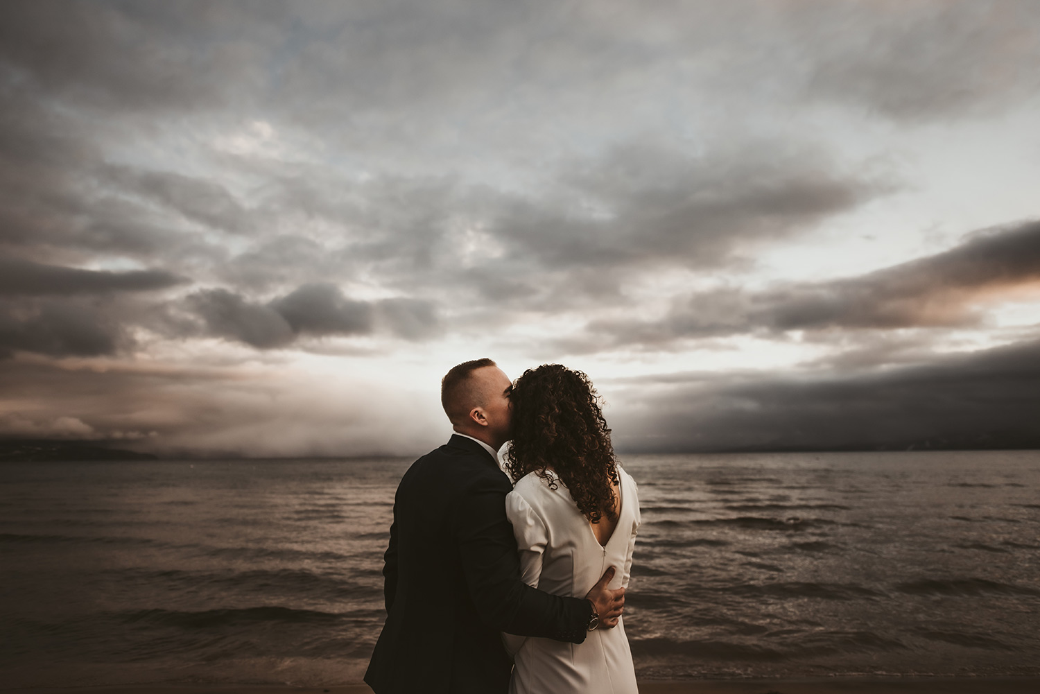 moody day on lake tahoe with bride and groom on shore
