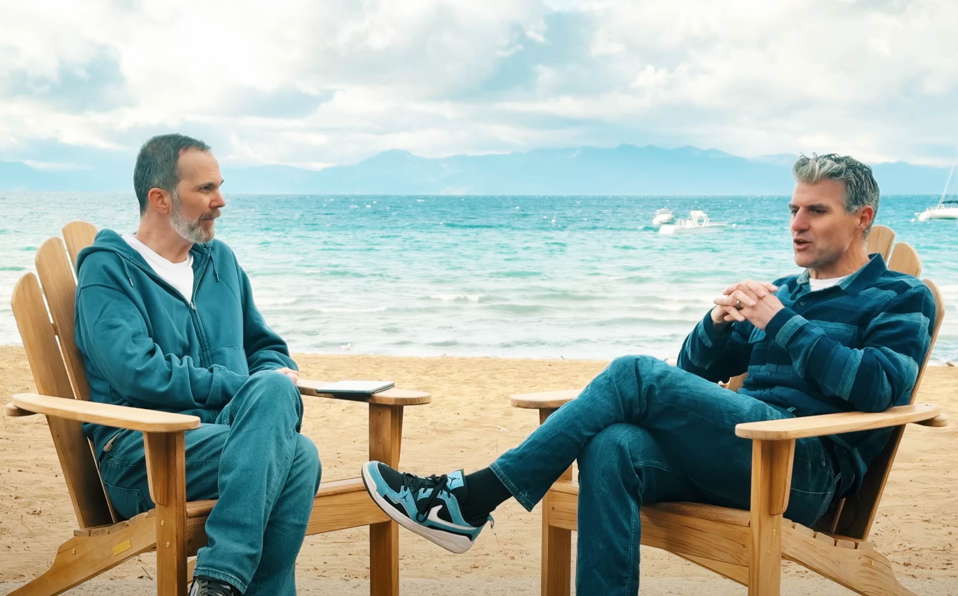 Two men sitting on adirondack chairs with Lake Tahoe in the background